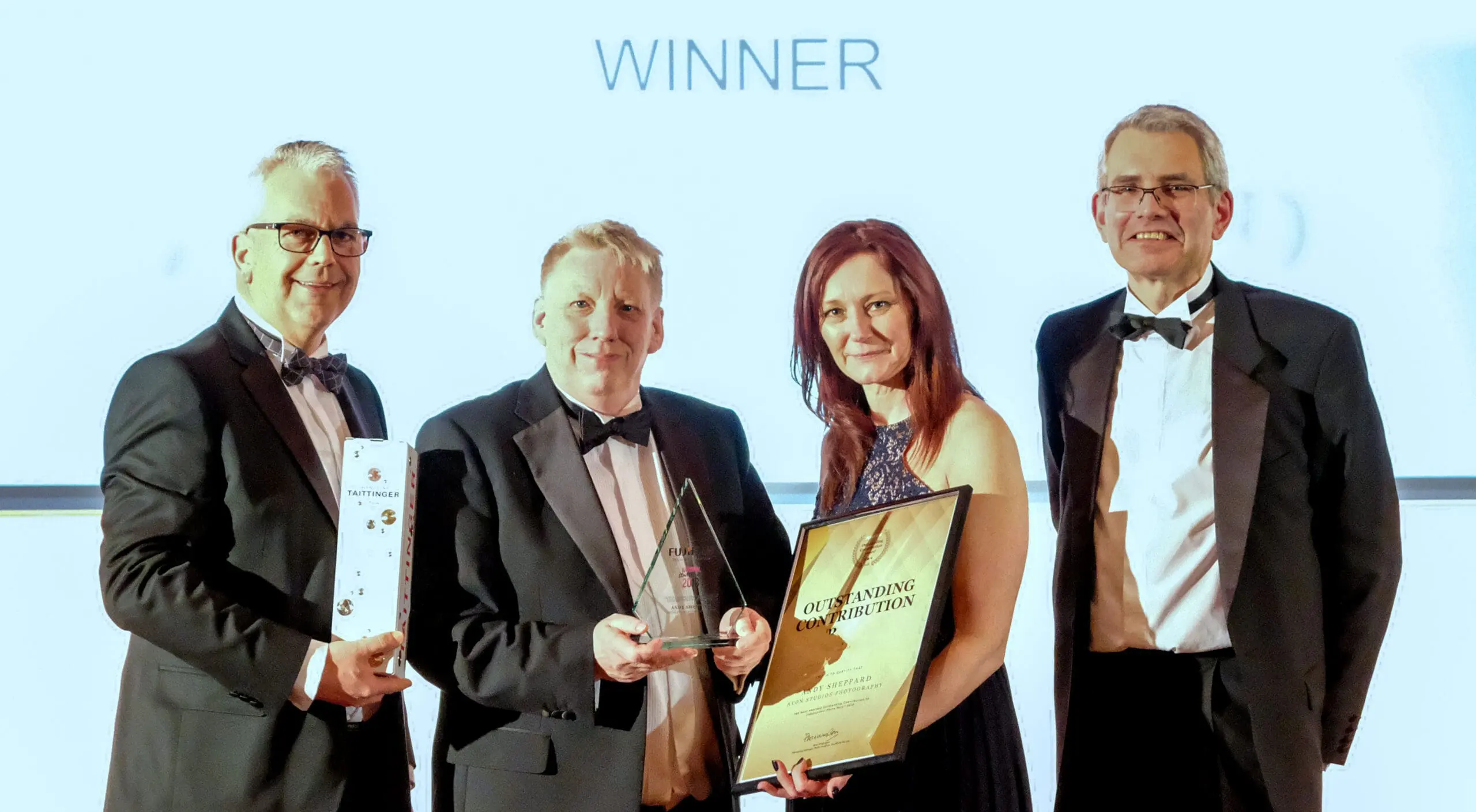 Group holding awards at ceremony, smiling winners.